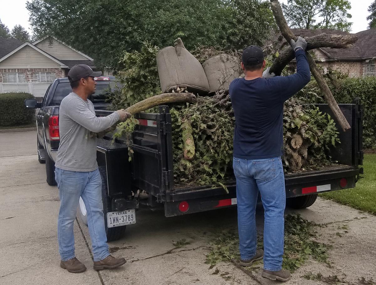 Crew loading brush, debris and old furniture into a junk removal truck